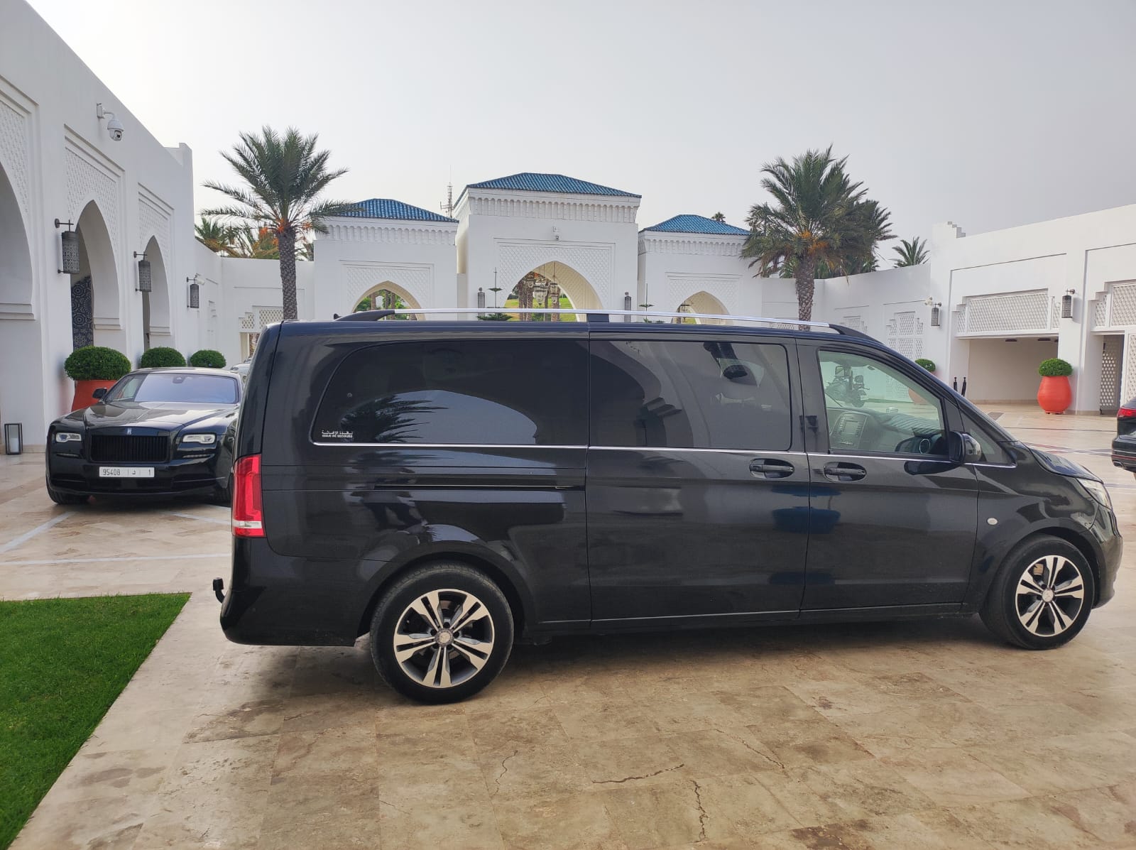 Black Mercedes-Benz V-Class parked in front of a white Moroccan palace